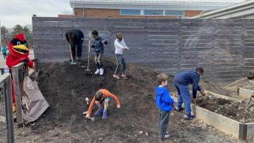 Children helping clean up the garden at Winter Wonderland with the Abingdon Cardinal looking on
